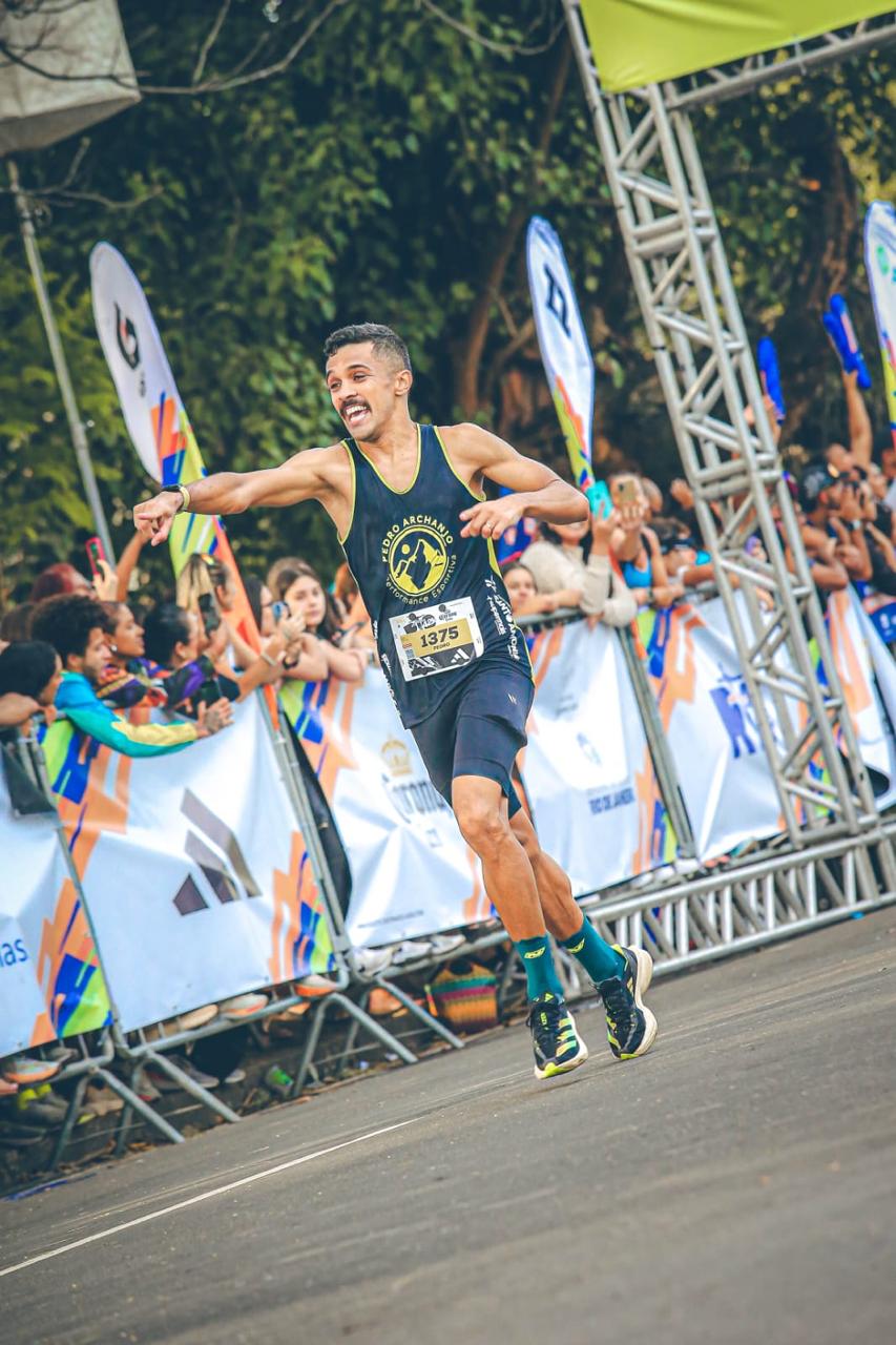 Atleta de assessoria de corrida uniformizado cruzando a linha de chegada